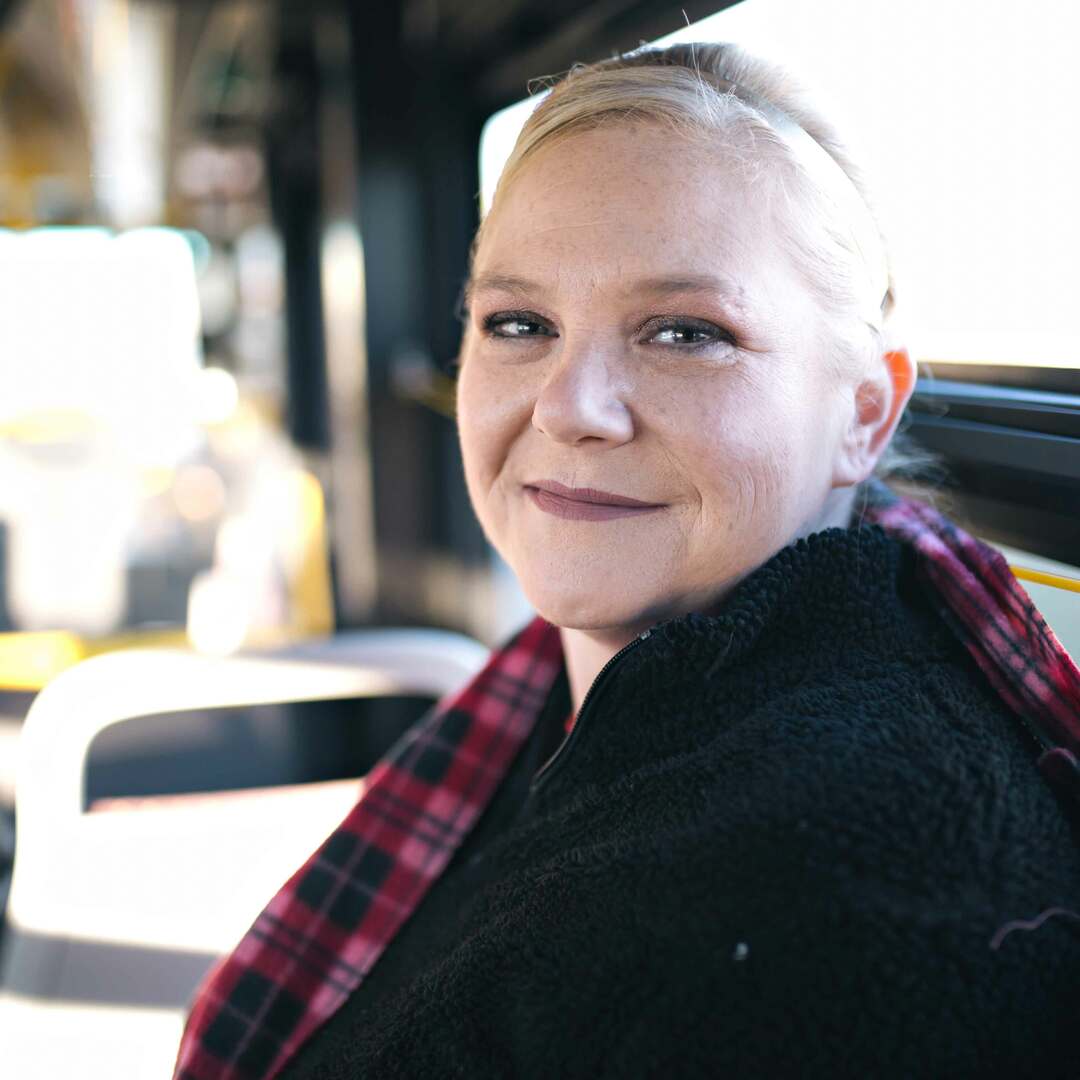 Photo of DART rider named Brandy sitting on a bus.